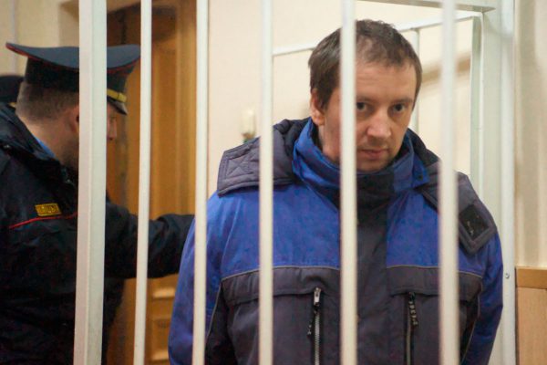 Конвой вводит российского священника Николая Киреева в клетку в зале судебных заседаний. Фото Сергея Серебро